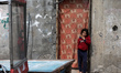 A Palestinian girl stand at the entrance of her home next to a distribution center run by...