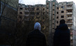 Two persons face a residential building in Sviatoshynskyi district affected by the shellin...