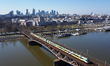 A drone view of Masovian Railways train on the Srednicowy Bridge and downtown in the backg...