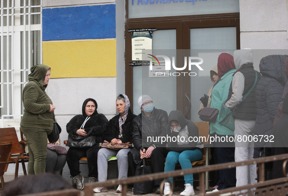 Ukrainian refugees who fled the war wait for receiving assistance at the entrance at the city humanitarian volunteer center for helping refu...