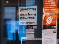 "please wear face mask in our store" sign is seen in front of Saturn, the electronic store in the city center of Cologne, Germany on April 4...