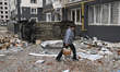 A woman goes near a damaged residential building in the recaptured by the Ukrainian army B...
