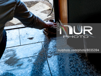 BUCHA, UKRAINE - APRIL 7, 2022 - A woman wipes the floor inside an apartment after the liberation of the city from Russian invaders, Bucha,...