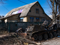 BUCHA, UKRAINE - APRIL 7, 2022 - A destroyed military vehicle is seen near a fence marked with the word 'People' after the liberation of the...