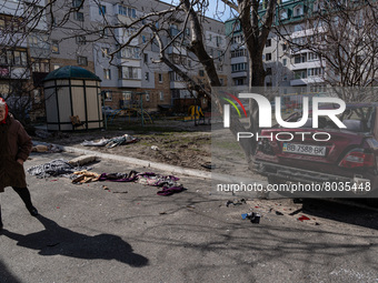 BUCHA, UKRAINE - APRIL 7, 2022 - An elderly woman stays on a street near a damaged car after the liberation of the city from Russian invader...