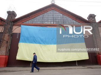 A worker walks next to a large national flag during a presentation of the new multi-section Odissey MAX tram, maded in the car repair worksh...