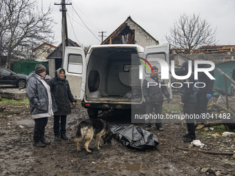 Relatives and neighbors stand next to a body of a person found under the rubble after the collapse of buildings destroyed by russian army in...