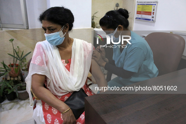 A health worker inoculates a woman with a precautionary dose of coronavirus vaccine at a hospital in New Delhi, India on April 10, 2022,  af...