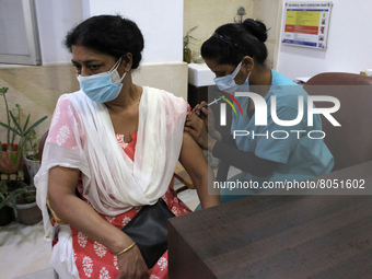 A health worker inoculates a woman with a precautionary dose of coronavirus vaccine at a hospital in New Delhi, India on April 10, 2022,  af...