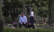 An Iranian woman walks past a man sitting on a bench in an urban park in downtown Tehran o...