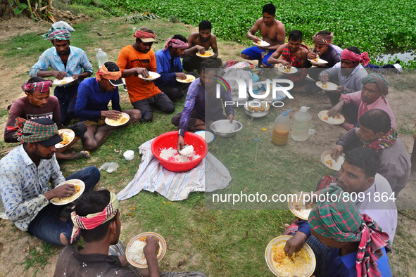 A group of workers eat their lunch as they take a break from harvesting paddy at a field Ashulia near Dhaka, Bangladesh, on April 18, 2022 