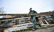ZAPORIZHZHIA, UKRAINE - APRIL 16, 2022 - A worker carries a wood plank as a 70-year-old bu...