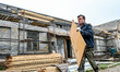ZAPORIZHZHIA, UKRAINE - APRIL 16, 2022 - A worker carries a wood board as a 70-year-old bu...