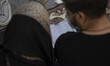 An Iranian couple read a copy of the Muslims holy book of Koran as they pray in the Imam K...