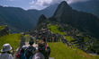 Tourists explore the ancient Inca city of Machu Picchu located in the Andes at an altitude...