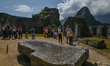 Tourists explore the ancient Inca city of Machu Picchu located in the Andes at an altitude...