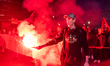 A protester holds a red smoke bomb mocratic Party) flag in protest against the involvement...