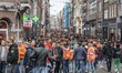 Crowds of people wearing mainly orange clothes and having the Dutch flag as seen in the st...