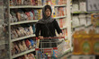 An Iranian woman carries products by a cart while shopping in Tehran's Megamall on Septemb...