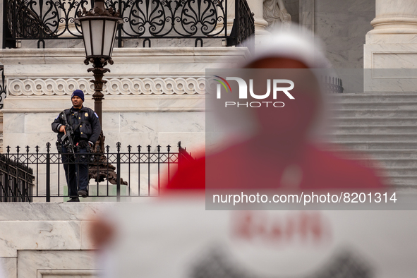 A Capitol Police officer armed with an assault rifle watches a protest by the Handmaids Army DC of the  Supreme Court's leaked preliminary d...