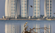 A grey heron bird perches on a trunk alongside trash at the north coast at Angke Kapuk Man...