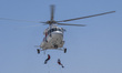 Two members of the Iranian Red Crescent Society climbs down from a helicopter while perfor...