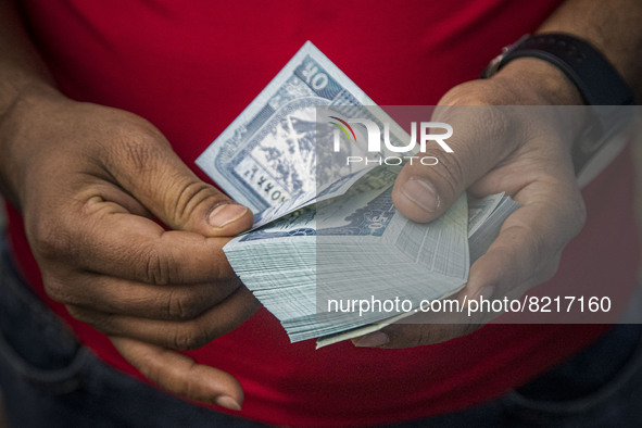 Closeup at a pack of 50 Nepalese Rupees while a man behind the counter is counting the paper currency. Money Exchange Centre office, a place...