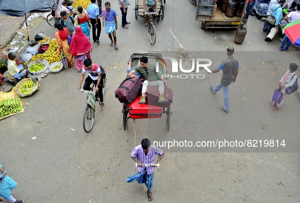 A rickshaw puller walks past a wholesale market in Kolkata, India, 13 May, 2022. A day labour carry a sack of vegetables in a wholesale mark...