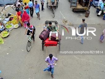 A rickshaw puller walks past a wholesale market in Kolkata, India, 13 May, 2022. A day labour carry a sack of vegetables in a wholesale mark...