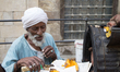 An old man crossed the 65-year-old Grilled potato vendor working in a hot Darb El Ahmar in...