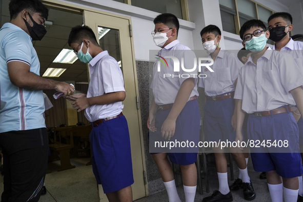 A teacher disinfects the hands of students entering a classroom at Assumption College resuming classes in Bangkok, Thailand, 17 May 2022. 