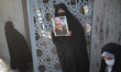 An Iranian veiled woman holds a portrait of the former commander of the Islamic Revolution...