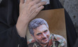 An Iranian veiled woman mourns as she holds a portrait of the Islamic Revolutionary Guard...