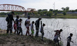 Migrants, most with children follow a path along the concertina wire where ultimatley they...
