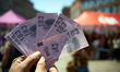 A protester shows false banknotes of €183 during the protest. Called by two trade unions,...