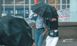 two women hold a umbrella walking in front of Dom Cathedral in Cologne, Germany on June 5,...