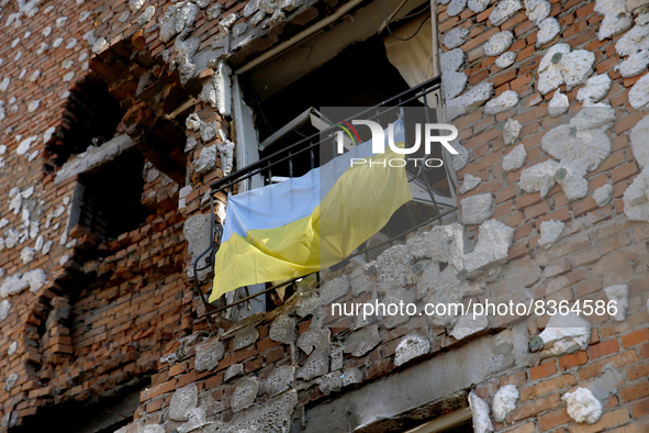 IRPIN, UKRAINE - JUNE 6, 2022 - A Ukrainian flag hangs on the railing of a window in an apartment block destroyed as a result of shelling by...