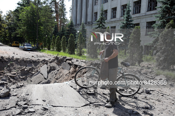 KHARKIV, UKRAINE - JUNE 20, 2022 - A man leaning on a bicycle looks at a crater after a Russian rocket landed near the Kharkiv State Zoovete...