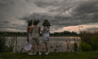 Three young women in a flower wreaths stand by the Wislok River during the Kupala Night ce...