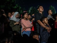 Villagers watch the fire battle, known locally as "sepak bola api", a fireball made from a coconut from a palm tree soaked during an annual...