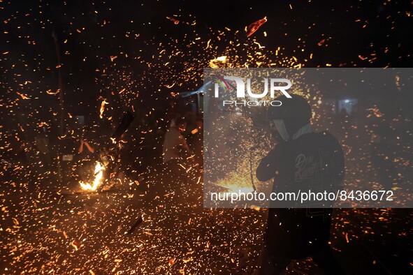 A man hits another with burning dried coconut leaves during a fire battle following an annual traditional event to express gratitude for the...