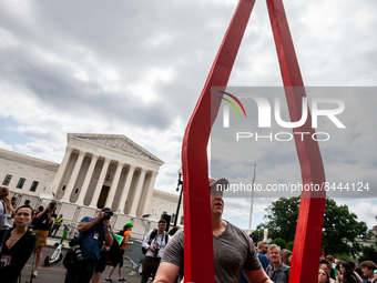A man removes a large red coat hanger entitled "Gates of Hell" after the Supreme Court issued its opinion on Dobbs v. JWHO.  The opinion rev...