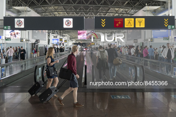 Morning departing and arriving passengers are seen carrying their luggage inside the terminal and the gates area of Brussels Zaventem Airpor...