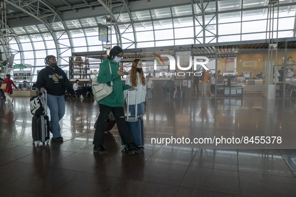 Passengers with facemasks are seen inside the terminal. Morning departing and arriving passengers are seen carrying their luggage inside the...