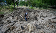 ORIKHIV, UKRAINE - JUNE 24, 2022 - A man stands in the crater left by a shell launched by...