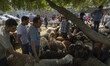 Muslims look at sheep while standing next to a flock of sheep during the Muslim holiday of...