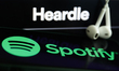 Heardle logo displayed on a laptop screen, Spotify logo displayed on a phone screen and he...