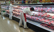 Workers hold packaged meat in a supermarket amid inflation is running at more than 60% in...