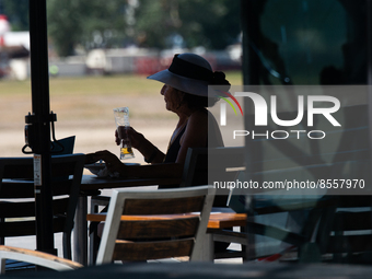 A woman drinks beer at a outdoor cafe  along the Rhine river in the mid of day in Duesseldorf, Germany on July 18, 2022 as a heat wave reach...