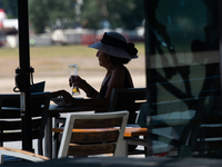 A woman drinks beer at a outdoor cafe  along the Rhine river in the mid of day in Duesseldorf, Germany on July 18, 2022 as a heat wave reach...